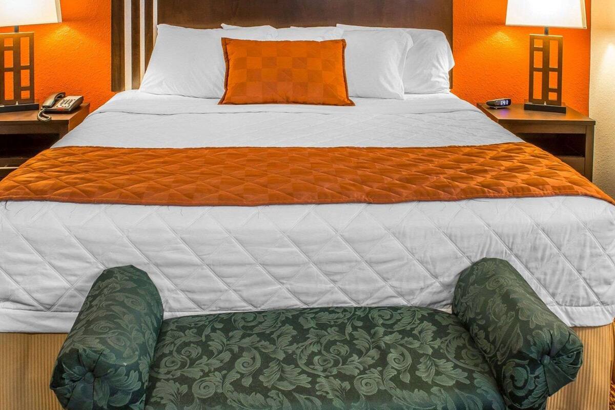 A hotel room with a large bed, two bedside tables, a telephone, and two lamps.