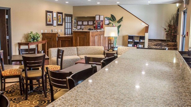 A hotel lobby with a long marble bar, seating area with sofas and chairs, a reception desk, and a staircase leading to an upper level. - Rodeway Inn Milford (Milford)
