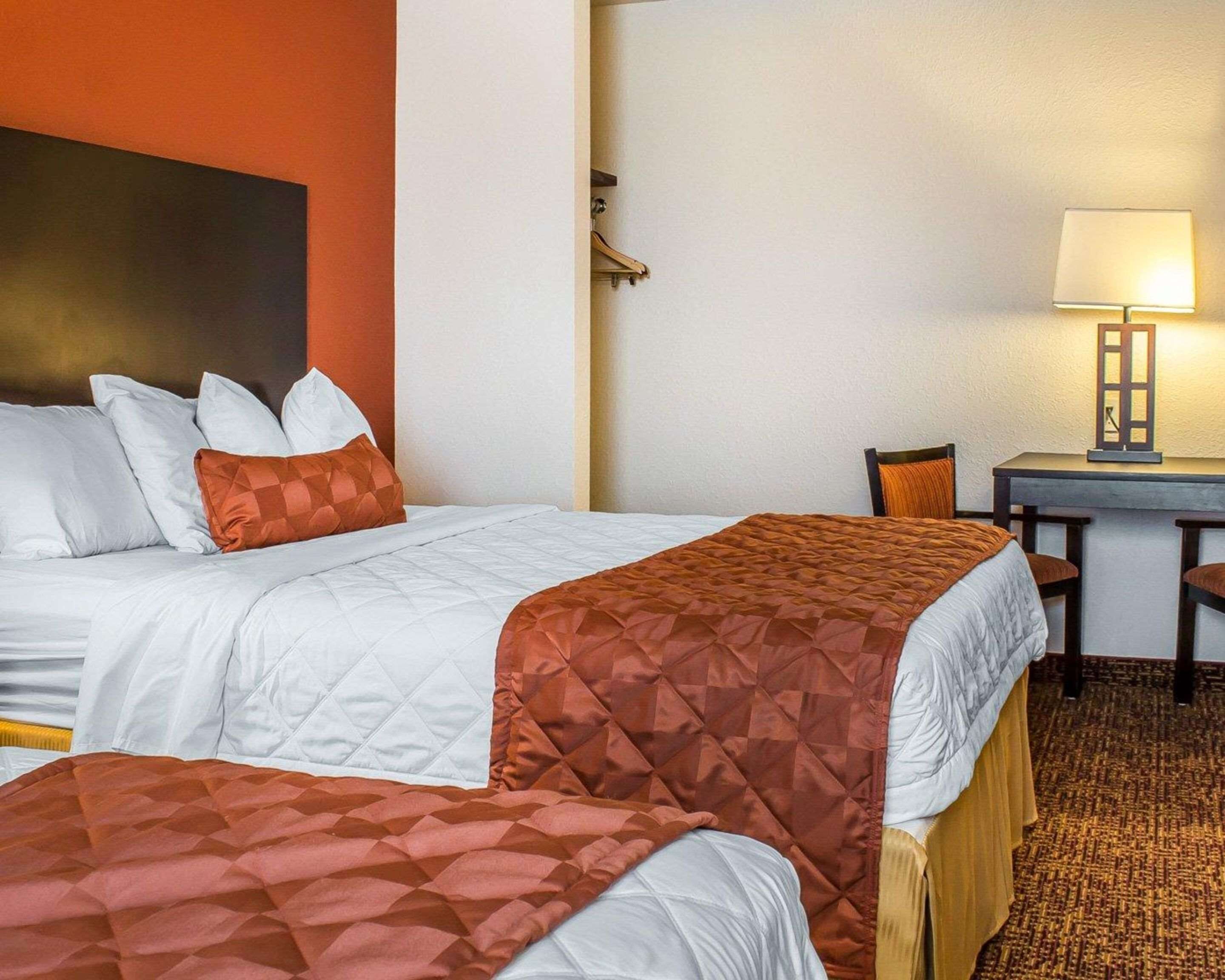 Habitación de hotel con dos camas, un escritorio y una silla.