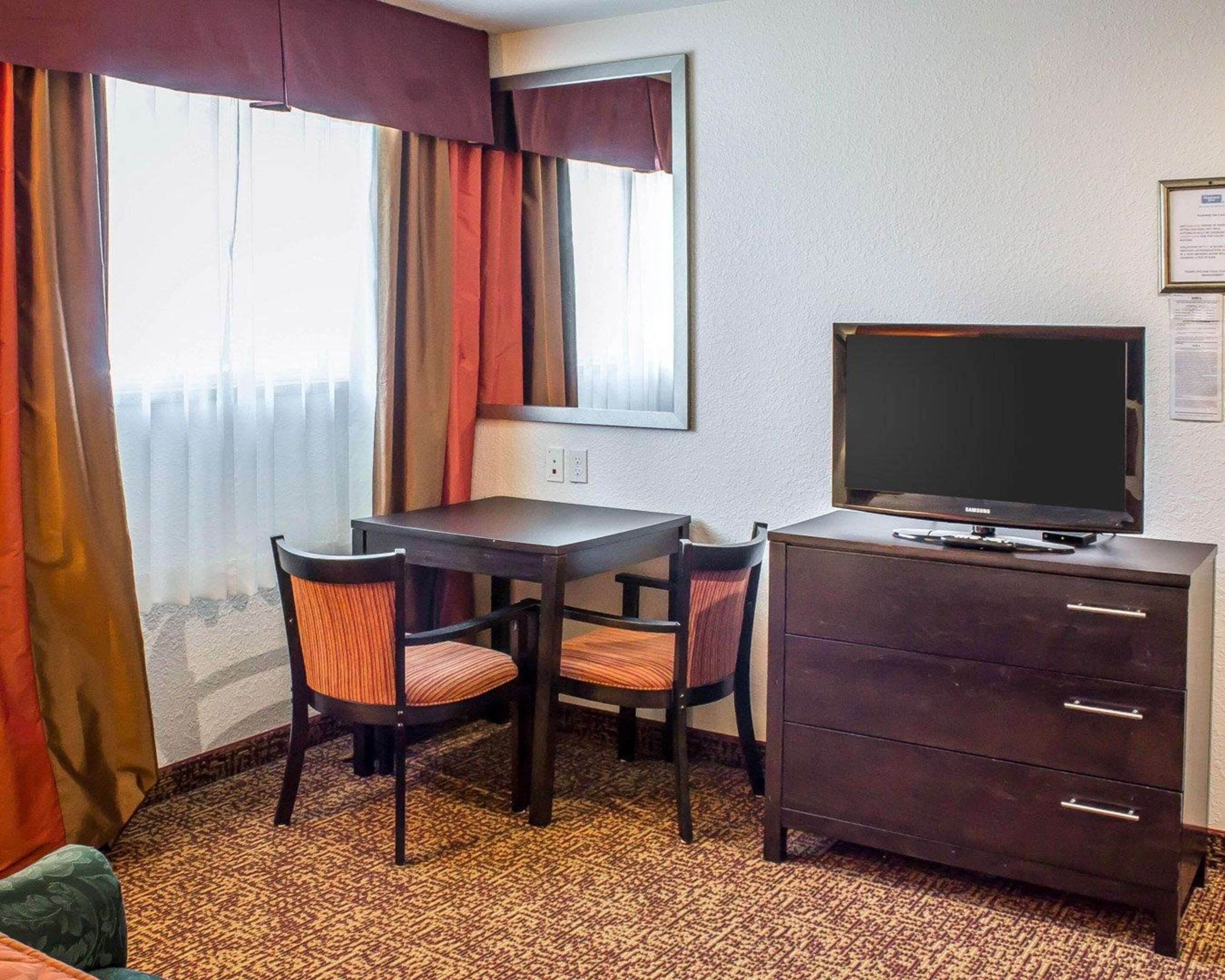 A small room with a desk, two chairs, a television, and a dresser.