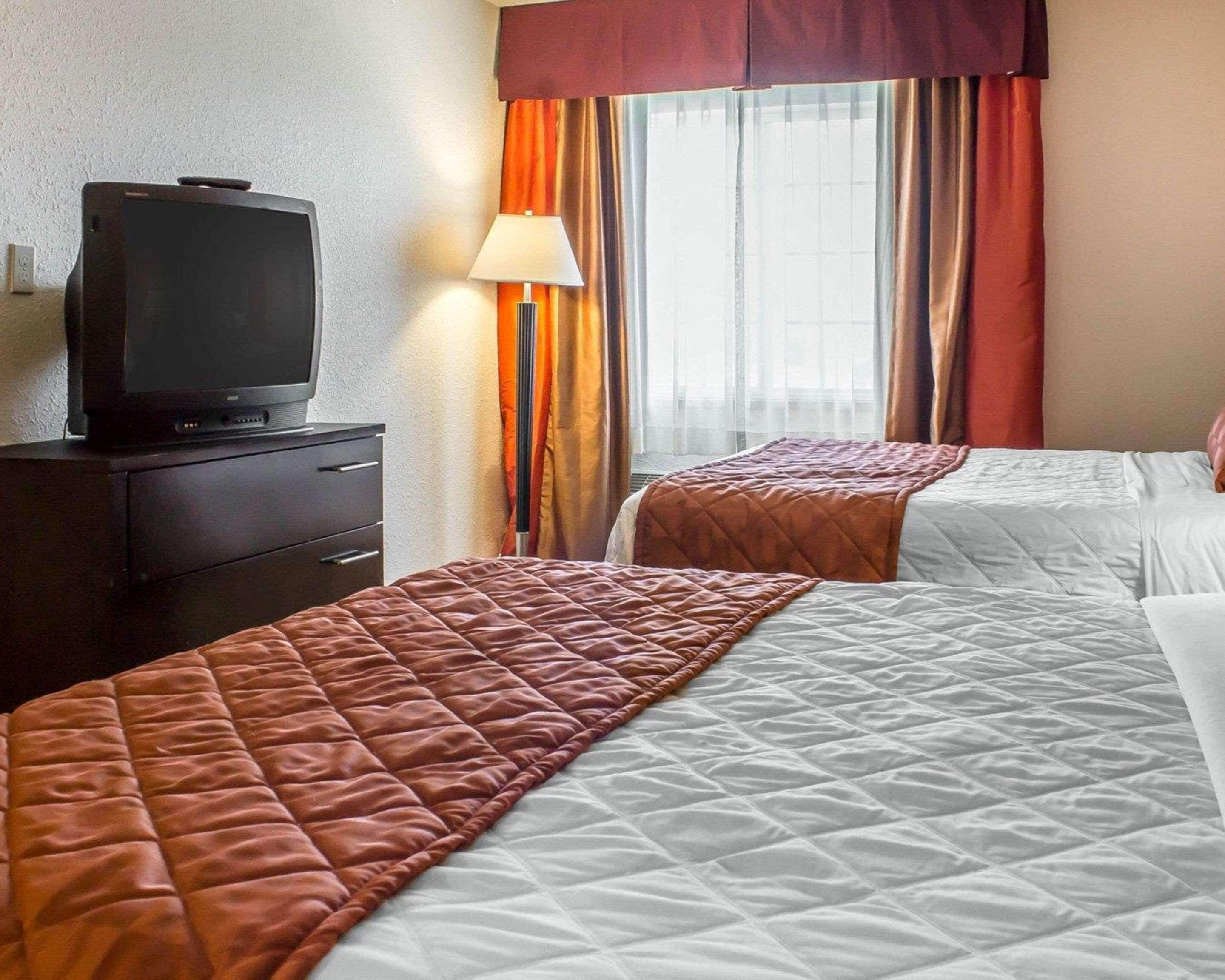 Una habitación de hotel con dos camas, un televisor en una cómoda y una ventana con cortinas.