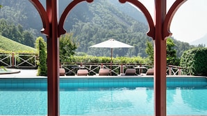 Un espace piscine offrant une vue sur un paysage montagneux, avec une terrasse en bois et des chaises longues.