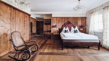 Una camera da letto con un letto di legno, una poltrona a dondolo, un lampadario e vista sull'esterno.