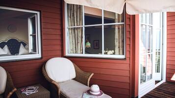A cozy room with wicker chairs, a cushioned bench, and a window with curtains.