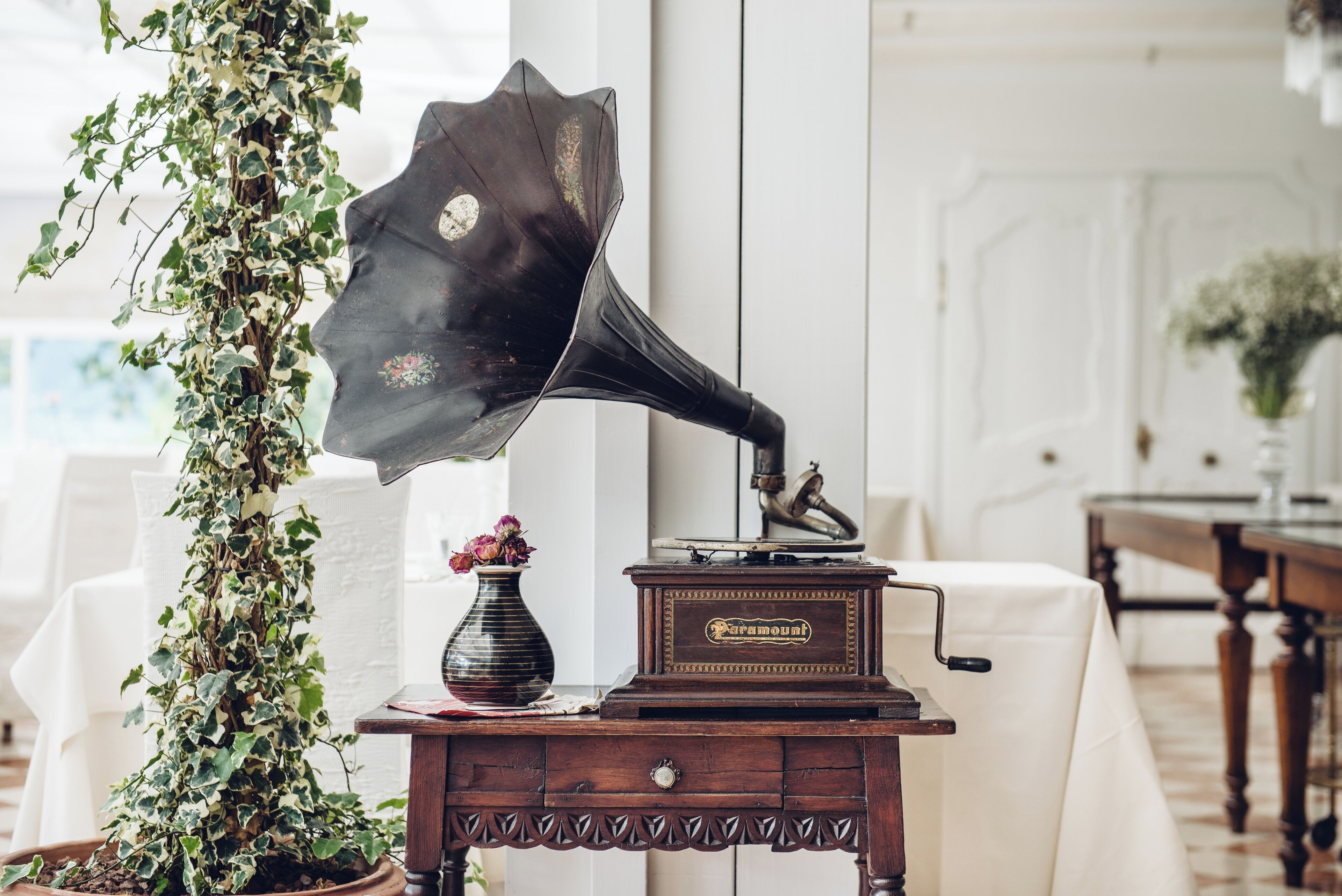 Un tocadiscos antiguo sobre una mesa de madera con un florero decorativo y una planta en maceta.
