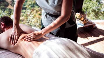 Een massagetherapie sessie in een kamer met een houten vloer en uitzicht op groen.