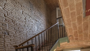 A staircase with a wooden handrail and metal balusters, leading to a landing with a window overlooking greenery. - Barbara (BARCELONA)