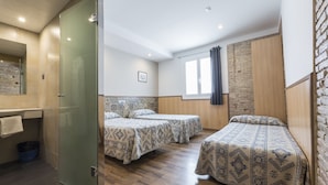 A room with two beds, a bathroom, and a brick wall. - Barbara (BARCELONA)