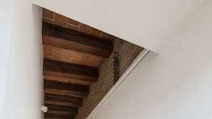 A narrow hallway with wooden flooring and a sloped ceiling with exposed beams. - Barbara (BARCELONA)