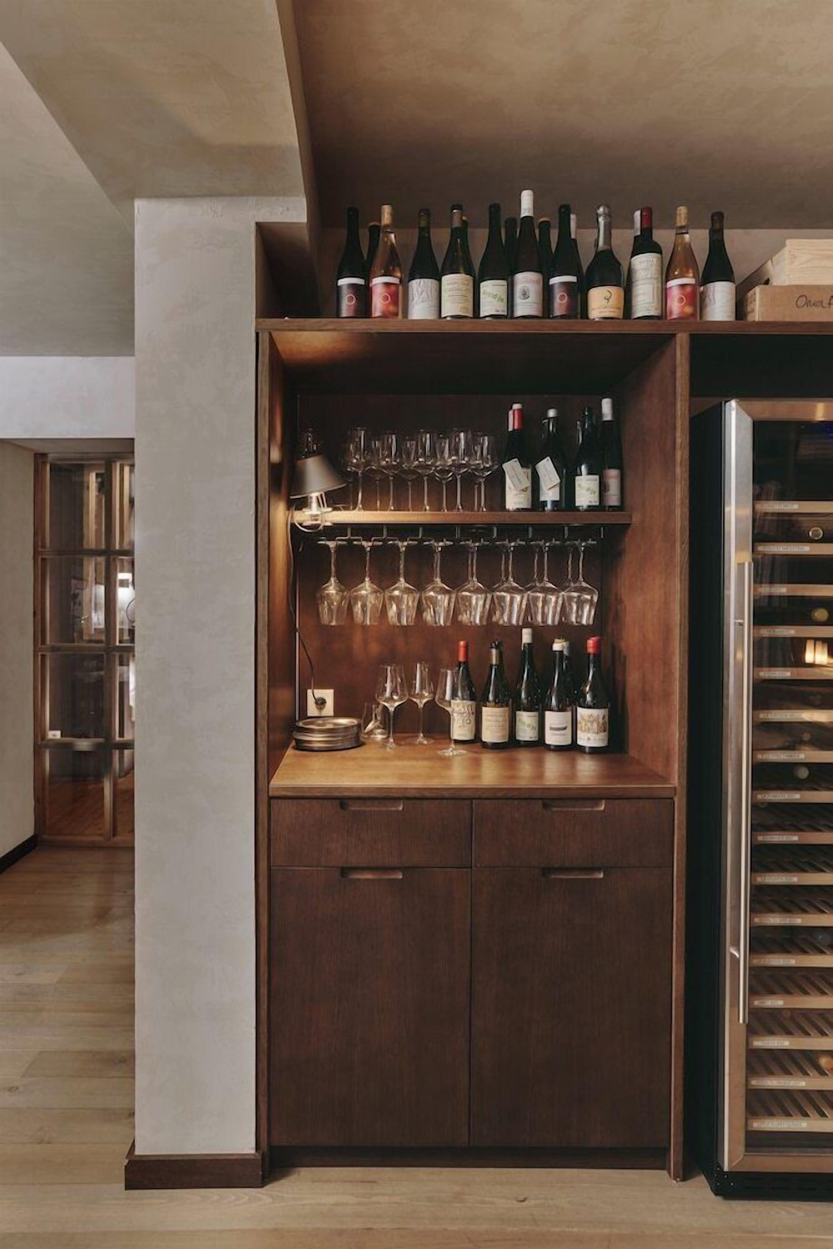A wine storage unit with shelves for bottles and glasses, a wine cooler, and a wooden cabinet.