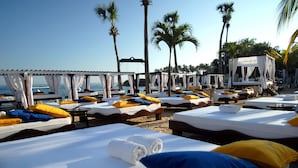 A beachside hotel with multiple sunbeds arranged in rows, some with umbrellas and others without. - Lifestyle Crown Residence Suites - All Inclusive (Puerto Plata)