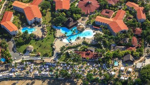 An aerial view of a resort with multiple buildings, a beach, and a large swimming pool. - Lifestyle Crown Residence Suites - All Inclusive (Puerto Plata)