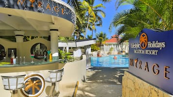 A poolside area with a bar, lounge chairs, and a sign for 'Lifestyle Holidays Vacation Resort'.