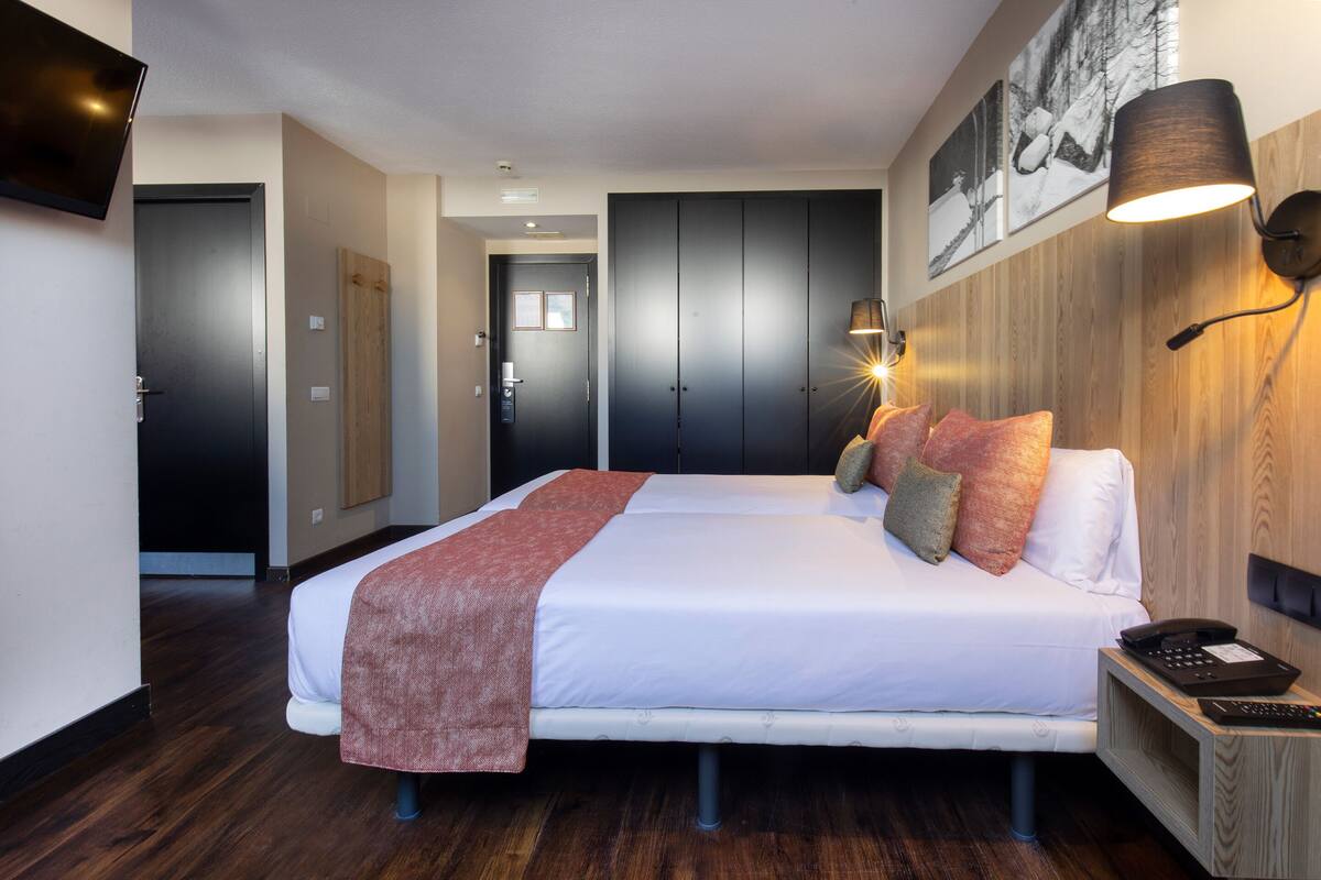 A hotel room with a bed, bedside lamp, and a telephone.
