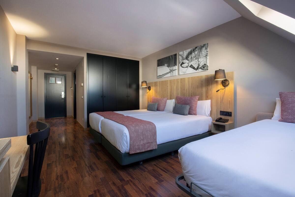 A modern hotel room with a large bed, bedside tables, a desk, and a wardrobe.