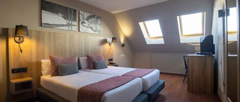 A bedroom with a large bed, two bedside tables, a desk, and a window.