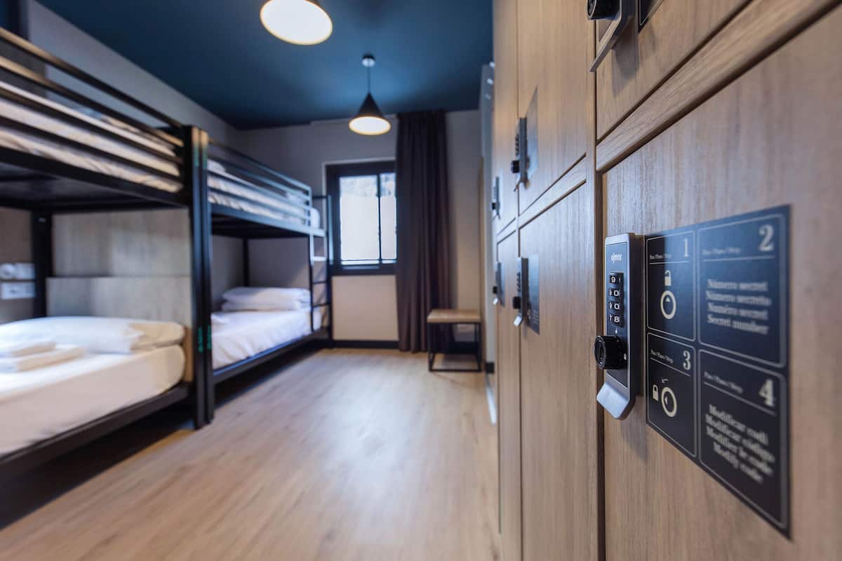 Habitación de hotel con literas, un escritorio y un armario con cerradura de combinación.