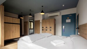 A hotel room with a large bed, wooden wardrobe, and a blue door. - Font Andorra Hostel by Nexta (La Massana)