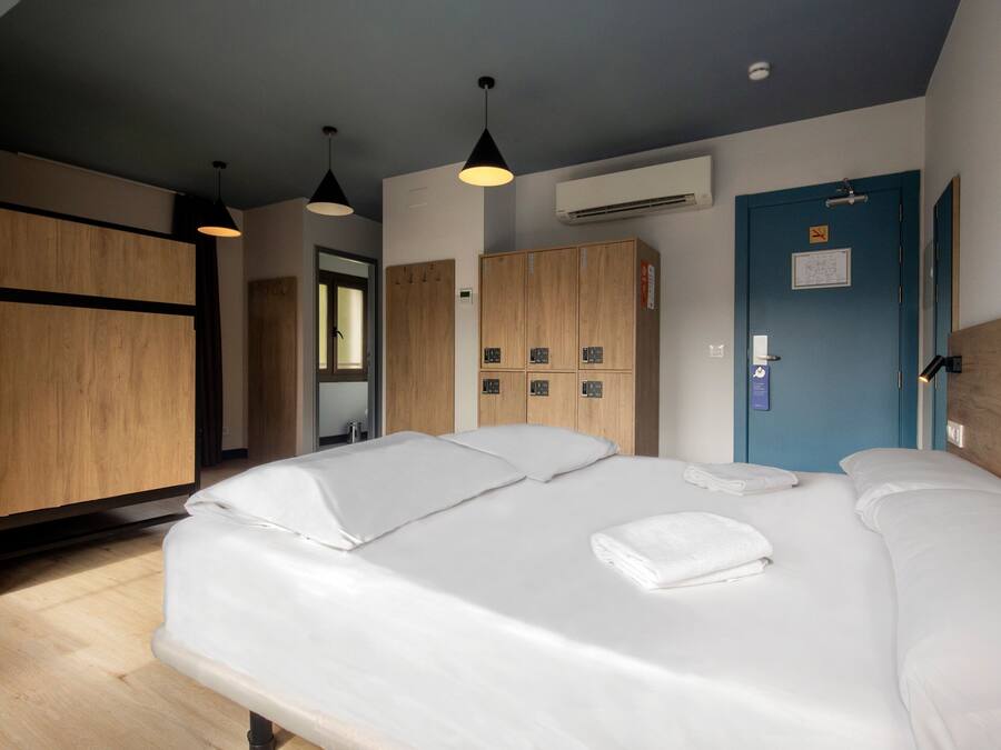A hotel room with a large bed, wooden wardrobe, and a blue door.