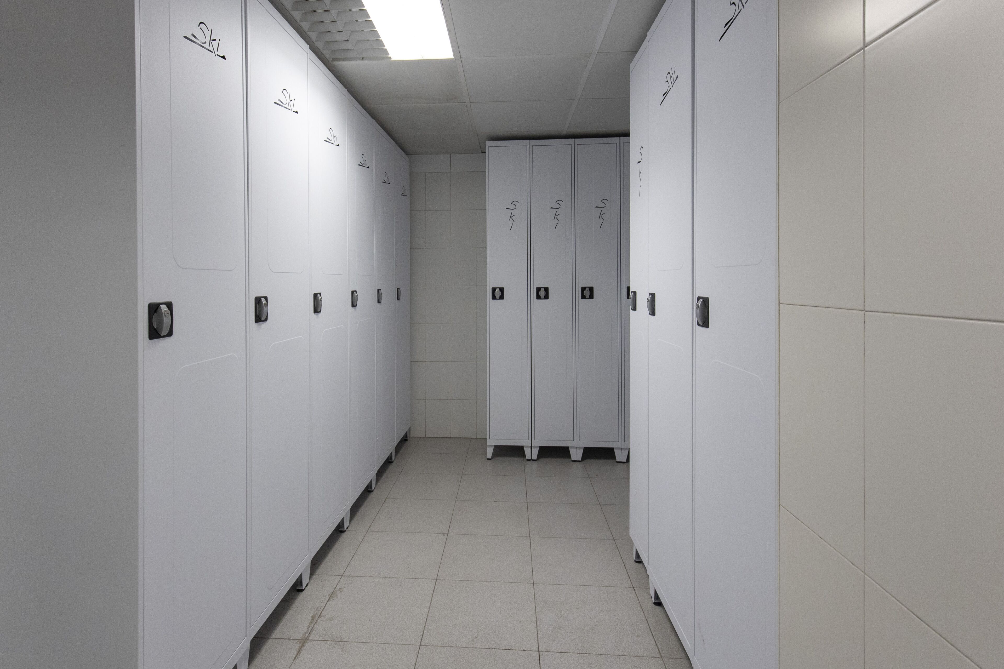A corridor with lockers and a tiled floor.