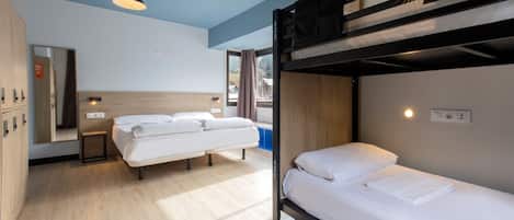 A room with bunk beds, a wooden floor, a mirror, a small table, and a window with curtains.