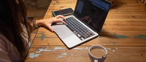 A wooden table with a laptop, a smartphone, and a cup of coffee.