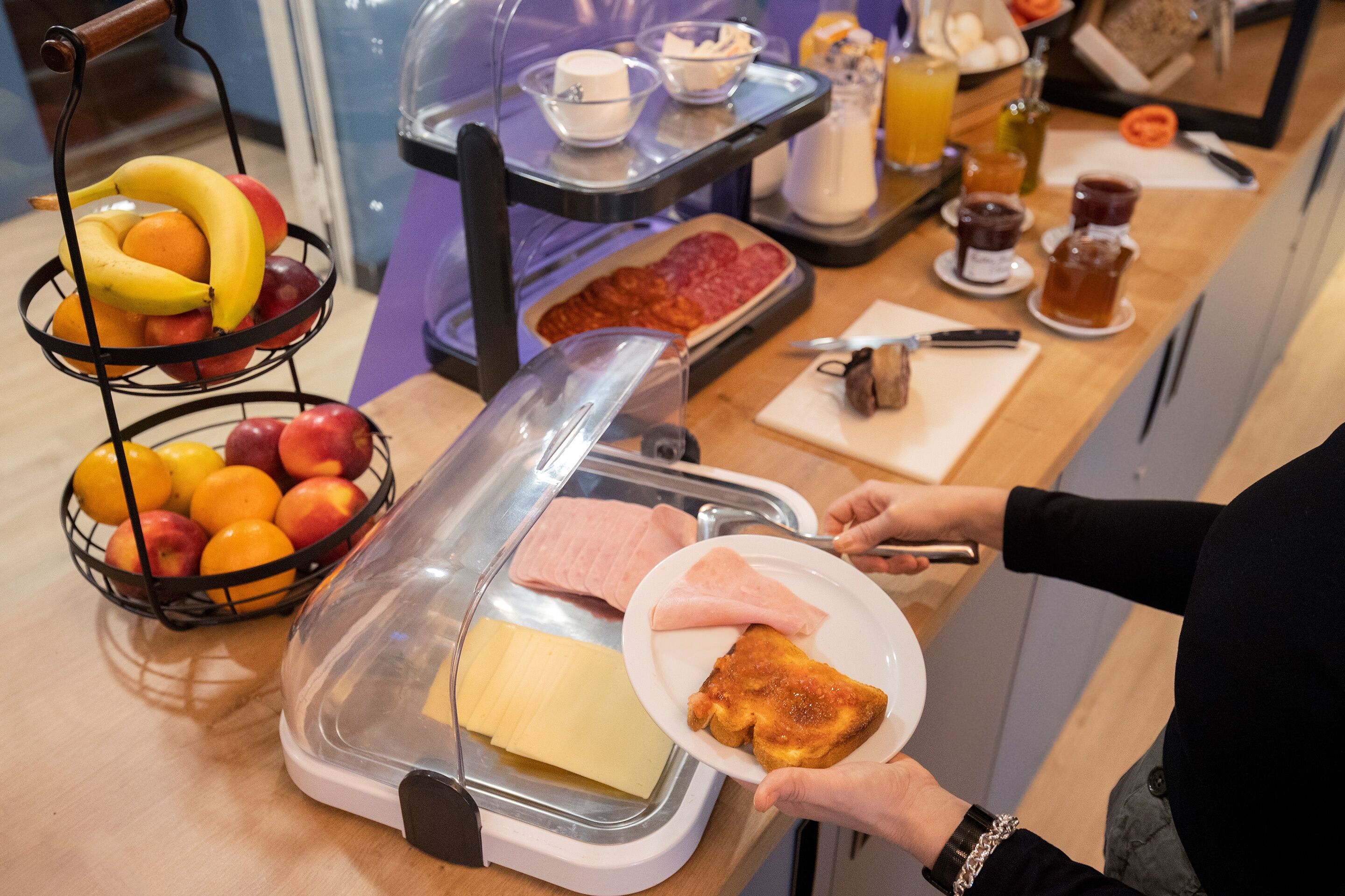 A breakfast buffet with various food items and a person serving themselves.