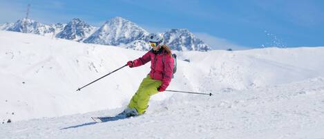 A person skiing on a snowy slope with mountains in the background.