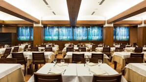 Een restaurant met verschillende tafels, elk voorzien van witte tafelkleden en houten stoelen.