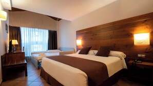 Een hotelkamer met een groot bed, een bureau, een stoel, een lamp en een houten hoofdeinde.