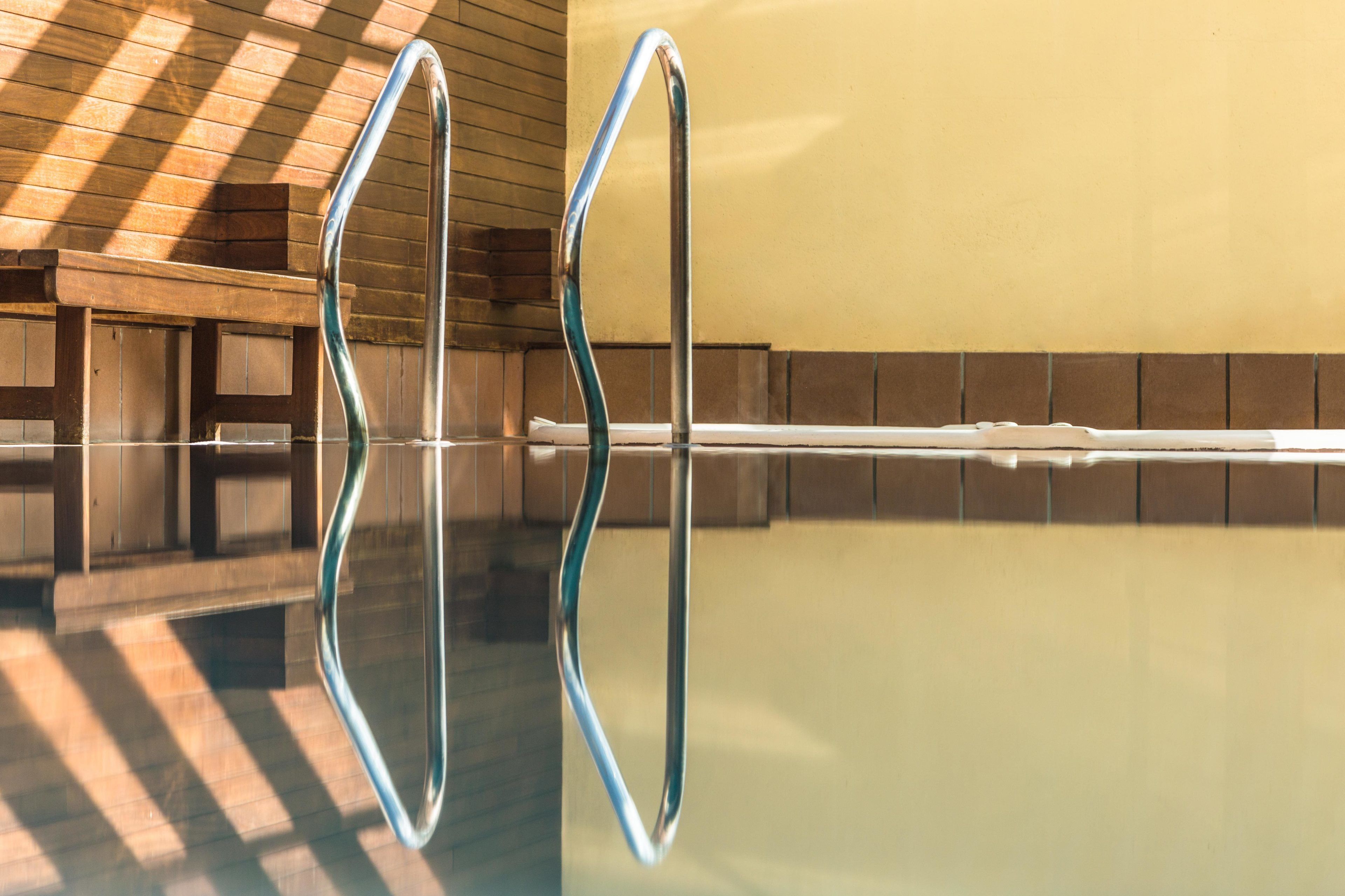 A swimming pool with clear water and metal handrails.