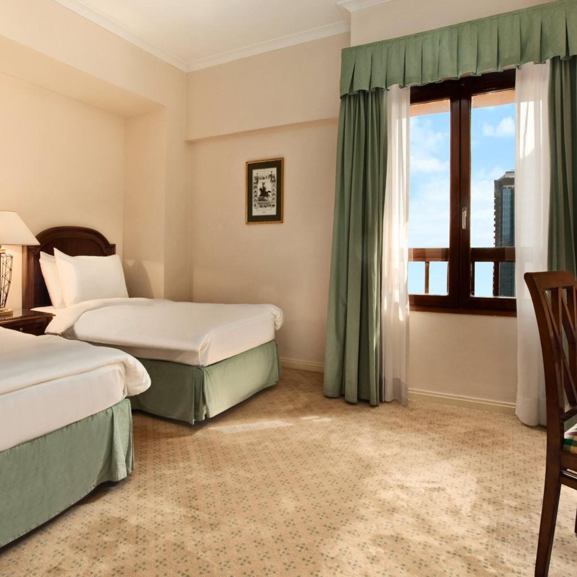 Habitación de hotel con dos camas, una ventana con cortinas, un cuadro enmarcado en la pared y una silla.