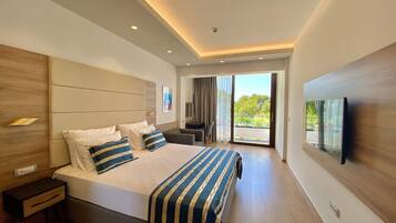 A modern hotel room with a large bed, a desk, a chair, and a TV mounted on the wall.