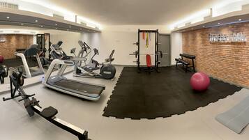 Un gimnasio moderno con cintas de correr, máquinas elípticas, un banco de pesas y pesas sueltas.