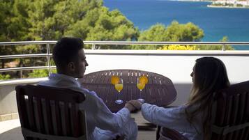 Two people seated at a table with a view of the sea and trees.