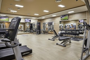 A gym with treadmills, weight machines, and dumbbells.