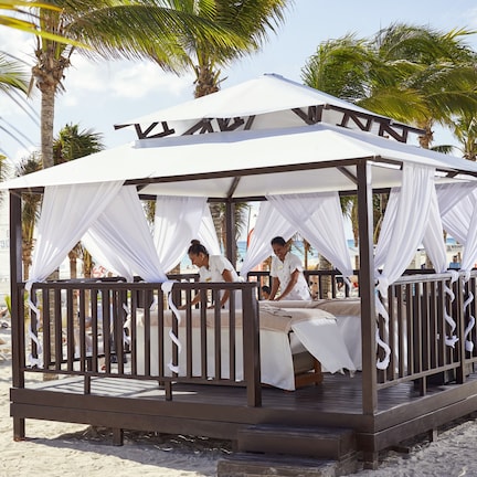 A beach cabana with a canopy and a wooden deck.