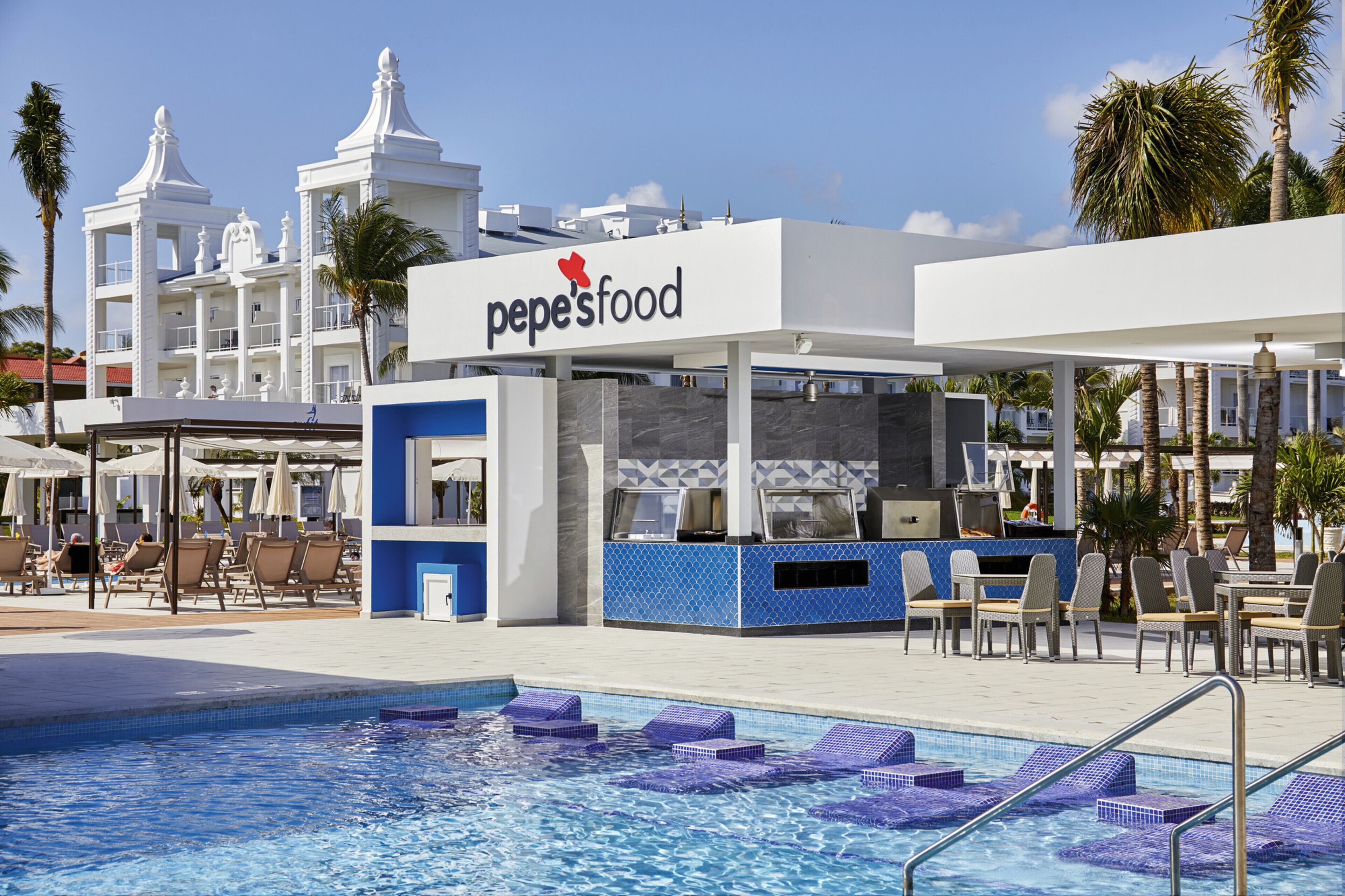 A poolside area with a restaurant named 'pepe'sfood', lounge chairs, and a pool with blue tiles.