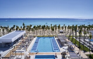 Una piscina al aire libre, sombrillas, sillones reclinables de piscina