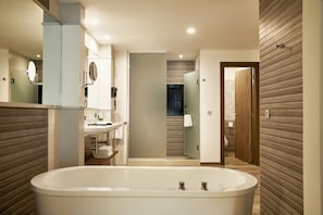 A modern bathroom with a large bathtub, a sink, and a mirror.