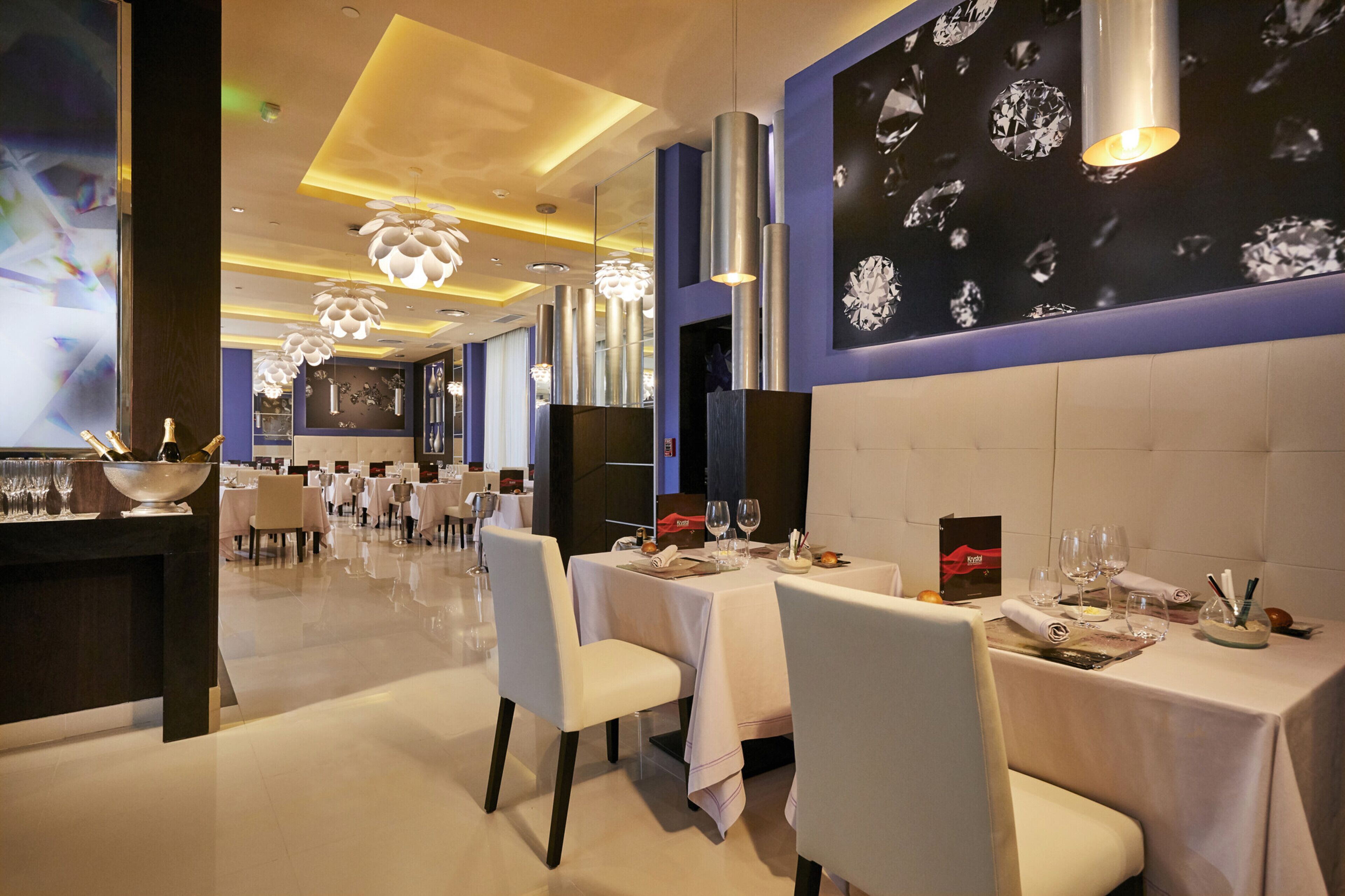 Un restaurante con mesas dispuestas para comer, una zona de bar y una pared con diseño de rombos.