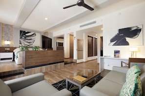 A modern hotel lobby with a reception desk, seating area, and a large artwork on the wall.