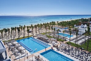 A resort with a large pool, beach, and palm trees.