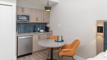Una cocina compacta con electrodomésticos modernos, un comedor con dos sillas y una pequeña mesa.