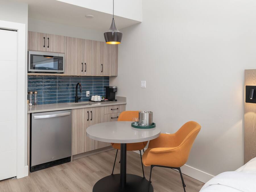Una cocina compacta con electrodomésticos modernos, un comedor con dos sillas y una pequeña mesa.