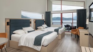 A modern hotel room with two beds, a desk, and a view of the sea. - Harrison Beach Hotel (Harrison Hot Springs)