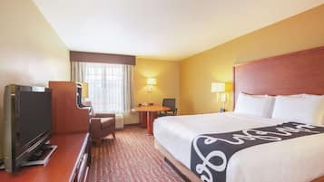 A hotel room with a bed, a TV, a desk, a chair, and a lamp.