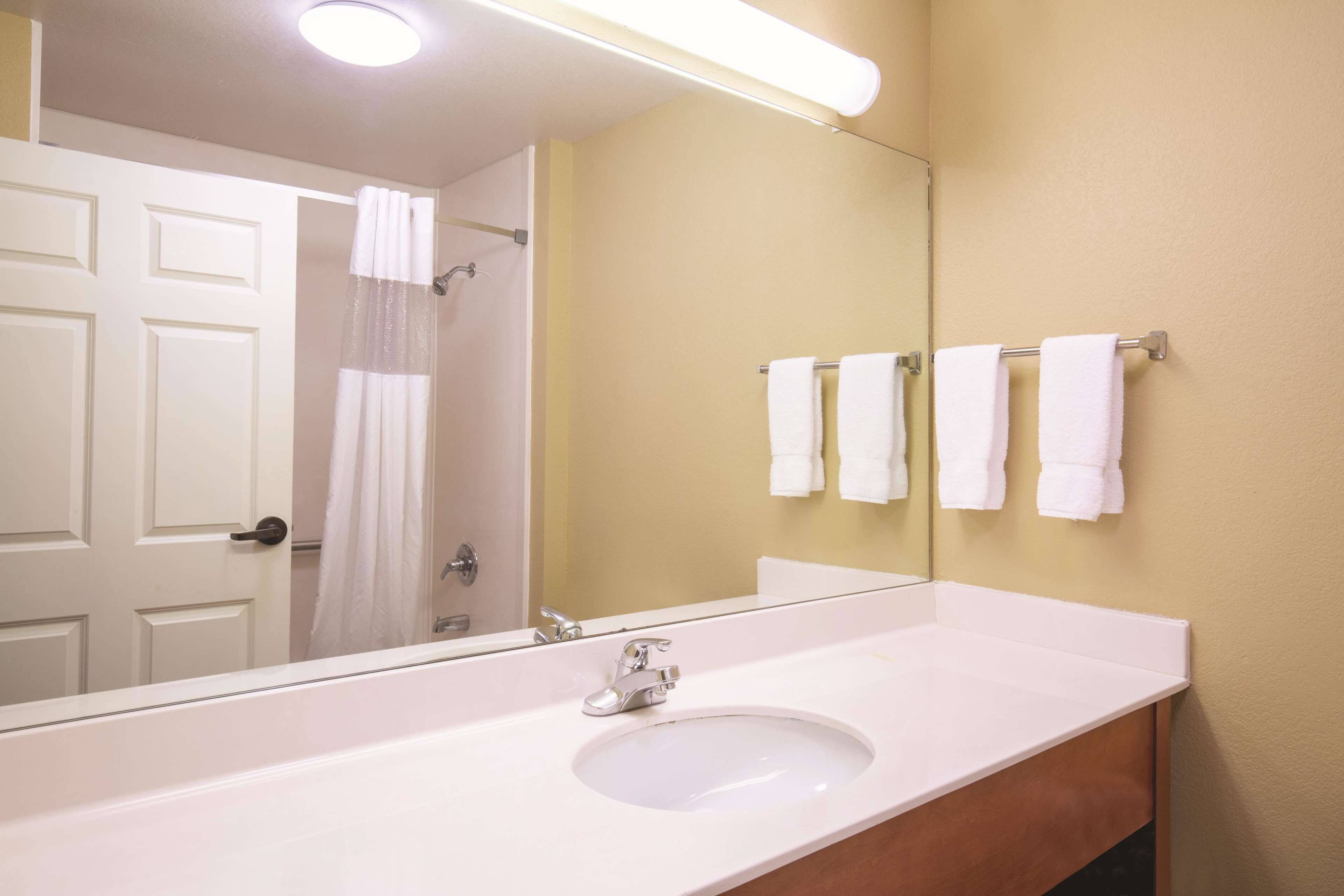 A bathroom with a white sink, a mirror, and a towel rack with multiple white towels.