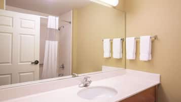 A bathroom with a white sink, a mirror, and a towel rack with multiple white towels.