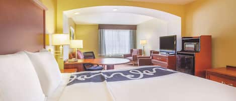 Una habitación de hotel con una cama grande, un escritorio con una silla, un televisor y un microondas.
